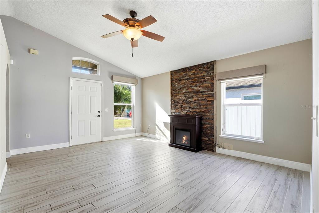10517 Rocking A Run Orlando, FL 32825 - Photo 11 of 29 an empty room with windows a fireplace and wooden floor