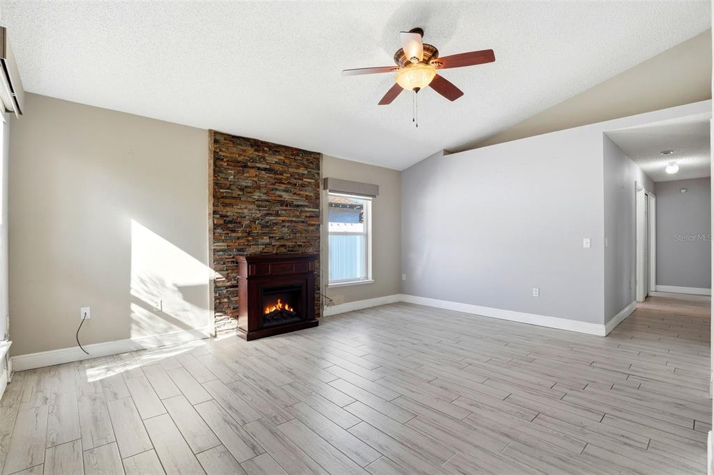 10517 Rocking A Run Orlando, FL 32825 - Photo 10 of 29 an empty room with wooden floor a chandelier fan and windows