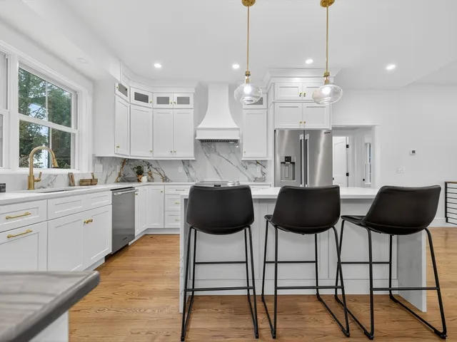 a kitchen with stainless steel appliances granite countertop a stove a refrigerator a sink a dining table and chairs with wooden floor