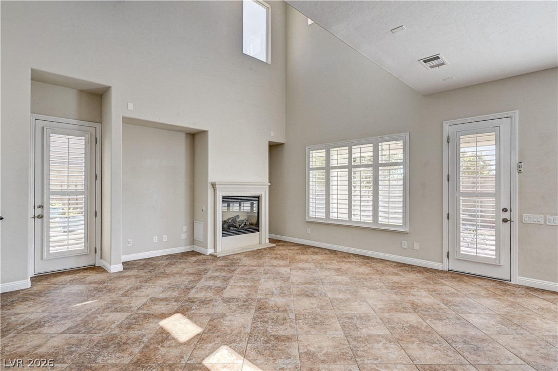 2793 Rosenhearty Drive Henderson, NV 89044 - Photo 19 of 85 This living room offers soaring ceilings and a cozy corner fireplace, creating an inviting atmosphere.