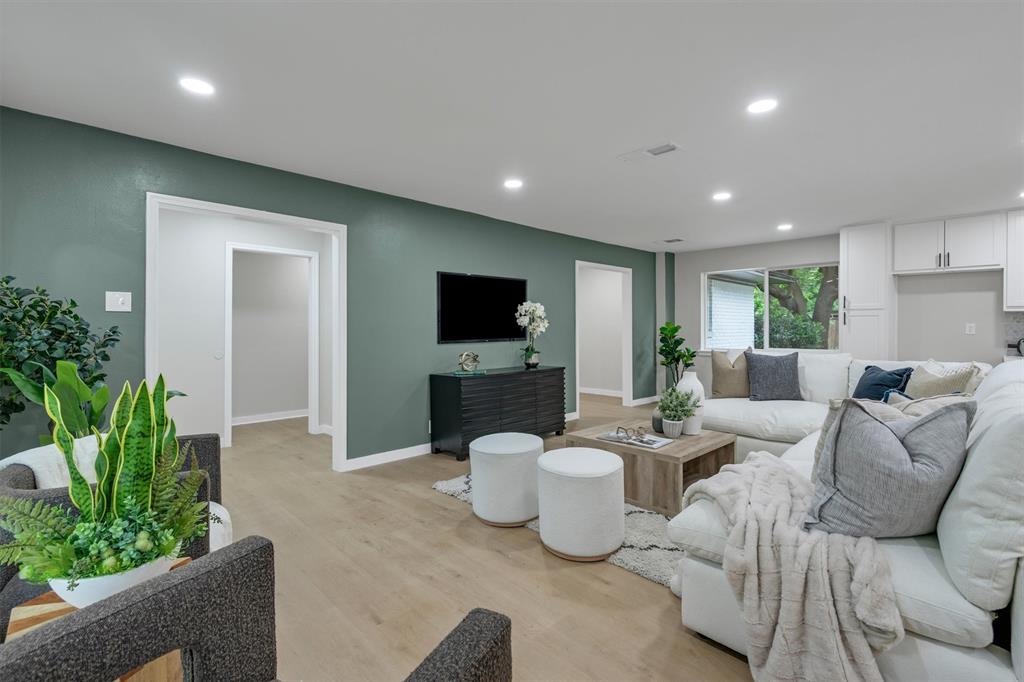 4815 Kelman Street Dallas, TX 75214 - Photo 1 of 37 Open-concept living space featuring wood-finish flooring, recessed lighting, a built-in media console, and a large window overlooking exterior landscaping