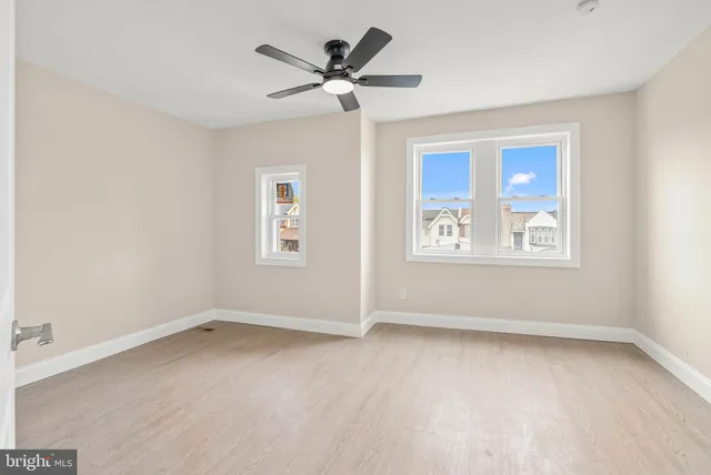 an empty room with ceiling fan and windows