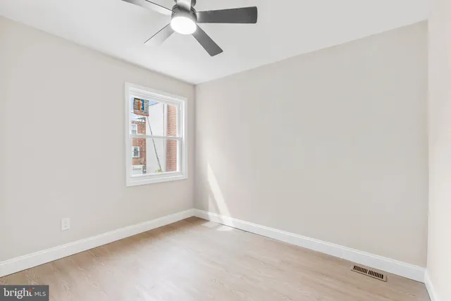 an empty room with a window and a fan