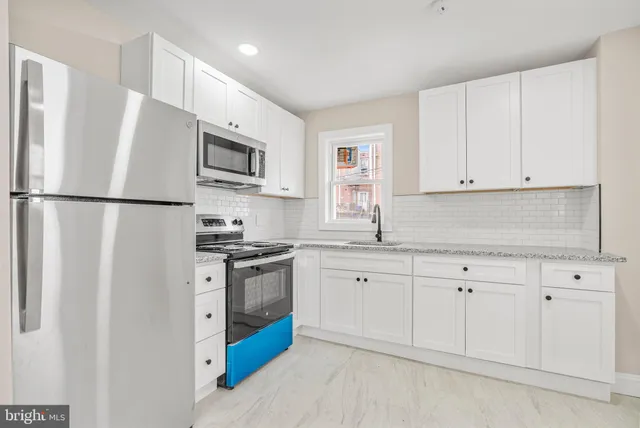 a kitchen with stainless steel appliances granite countertop white cabinets a refrigerator a sink a stove and white cabinets