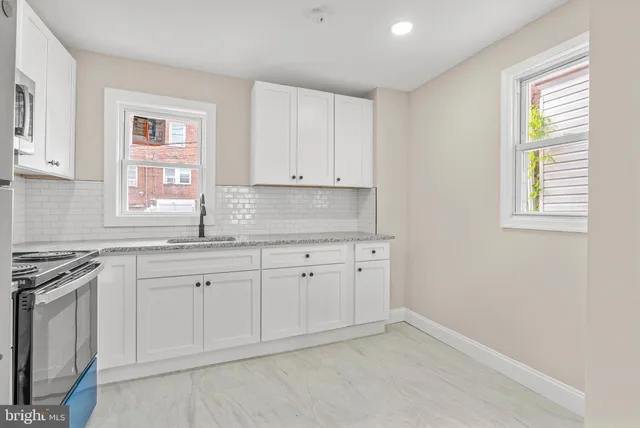 a kitchen with granite countertop white cabinets and window
