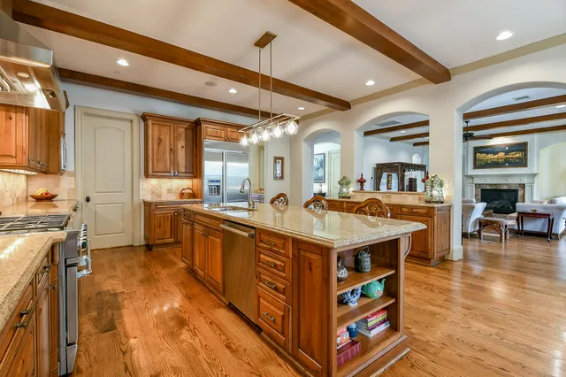 a large kitchen with stainless steel appliances a stove a sink dishwasher and a dining table with the living room view