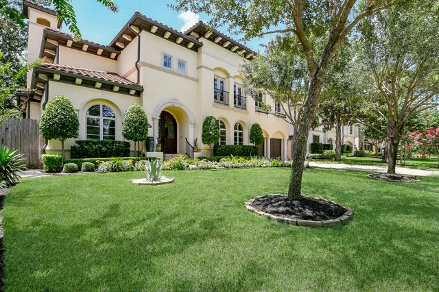 a front view of a house with garden and trees