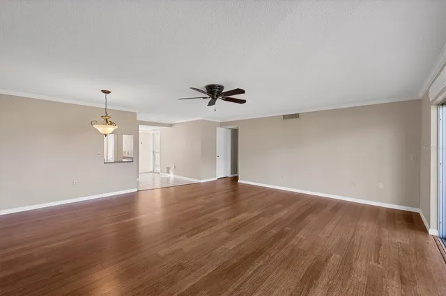 a view of empty room with wooden floor and fan