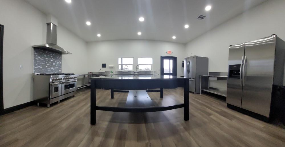 Lot 445 Ranchview Court Bowie, TX 76230 - Photo 4 of 17 a kitchen with stainless steel appliances a dining table chairs and wooden floor