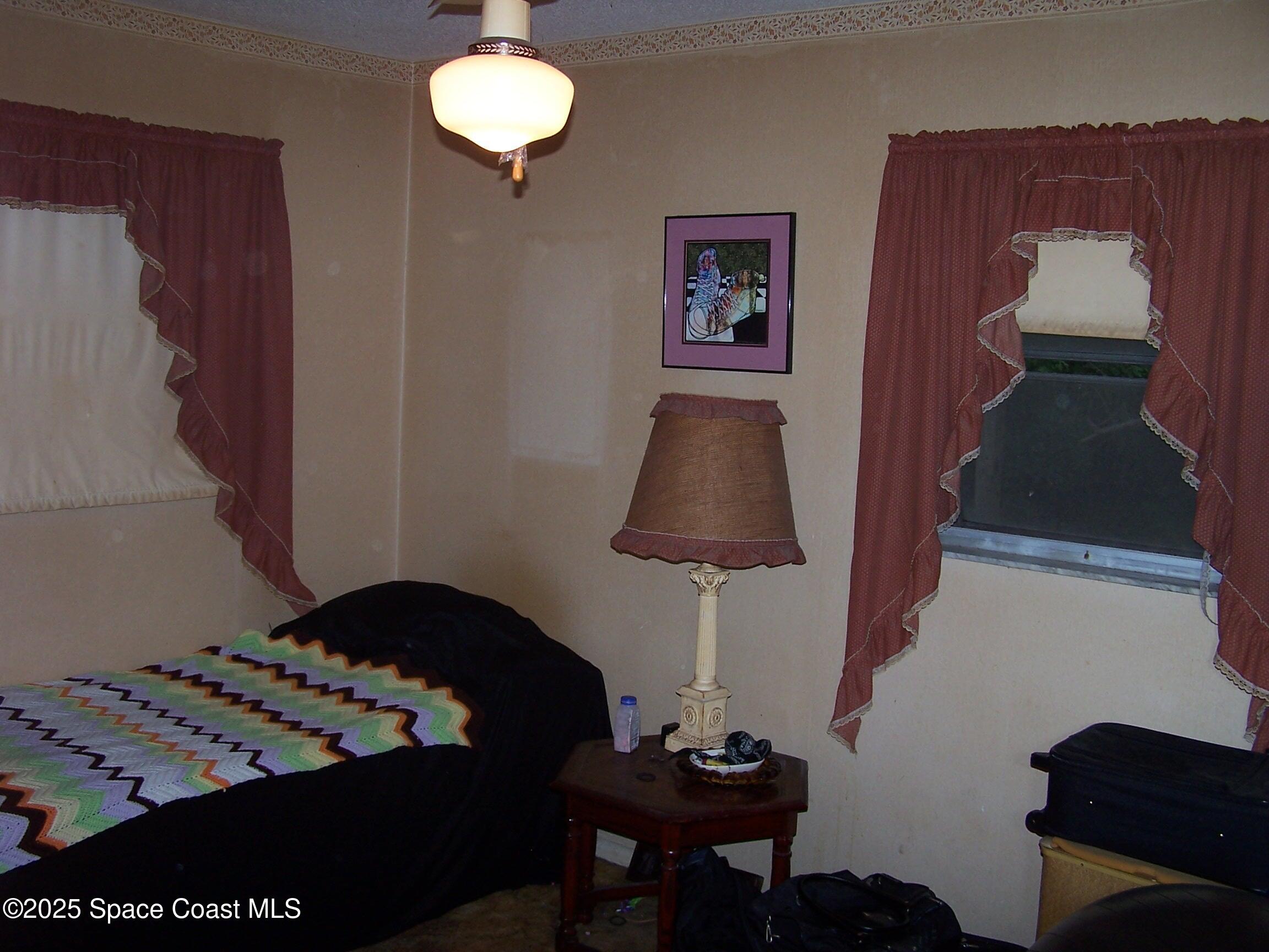 1545 Cunningham Avenue Merritt Island, FL 32952 - Photo 4 of 11 a bedroom with a bed and a lamp on dresser
