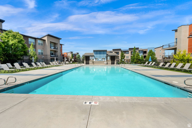 7713 Navarro View Court Midvale, UT 84047 - Photo 28 of 41 Expansive outdoor swimming pool with surrounding concrete decking, multiple lounge chairs, and a contemporary architectural building in the background