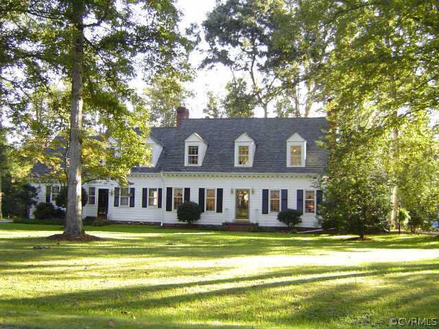 a view of a large pool with lawn chairs and large trees