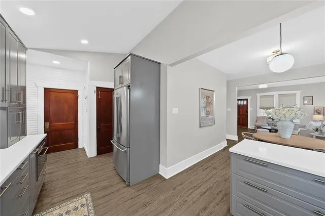 a kitchen with stainless steel appliances granite countertop a refrigerator a sink dishwasher a dining table and chairs with wooden floor