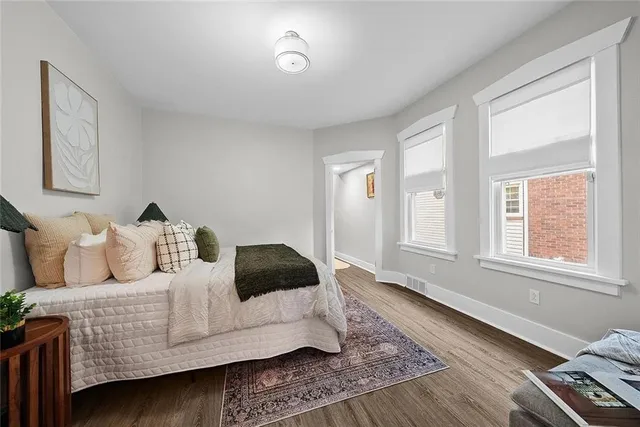 a bedroom with a bed wooden floor and couch
