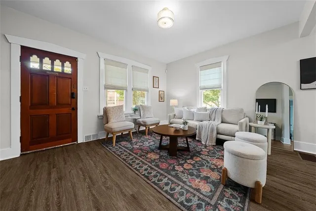 a living room with furniture two window and wooden floor