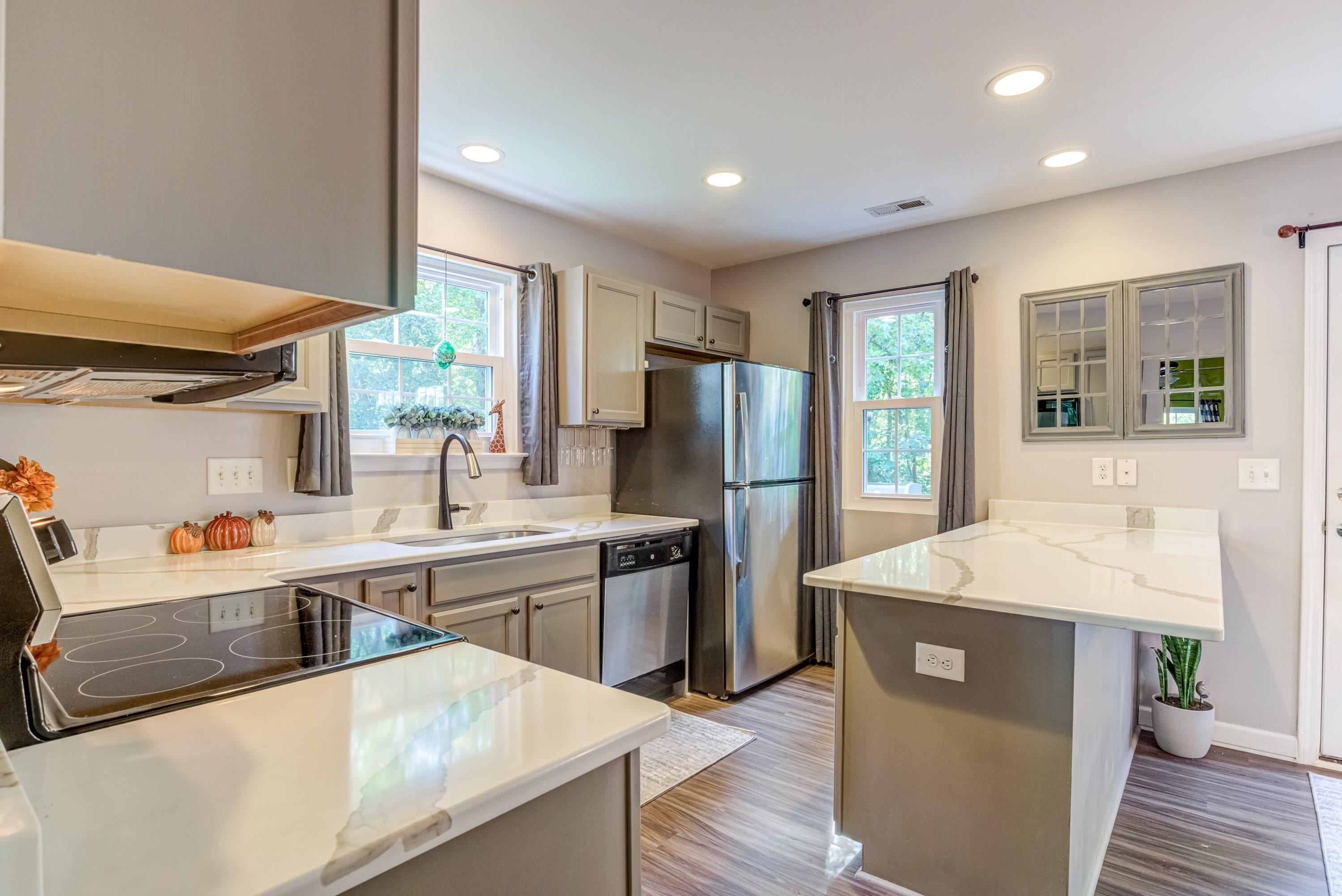 7726 Averette Field Drive Raleigh, NC 27616 - Photo 7 of 29 a kitchen with stainless steel appliances granite countertop a refrigerator a sink dishwasher a stove and white countertops with wooden floor