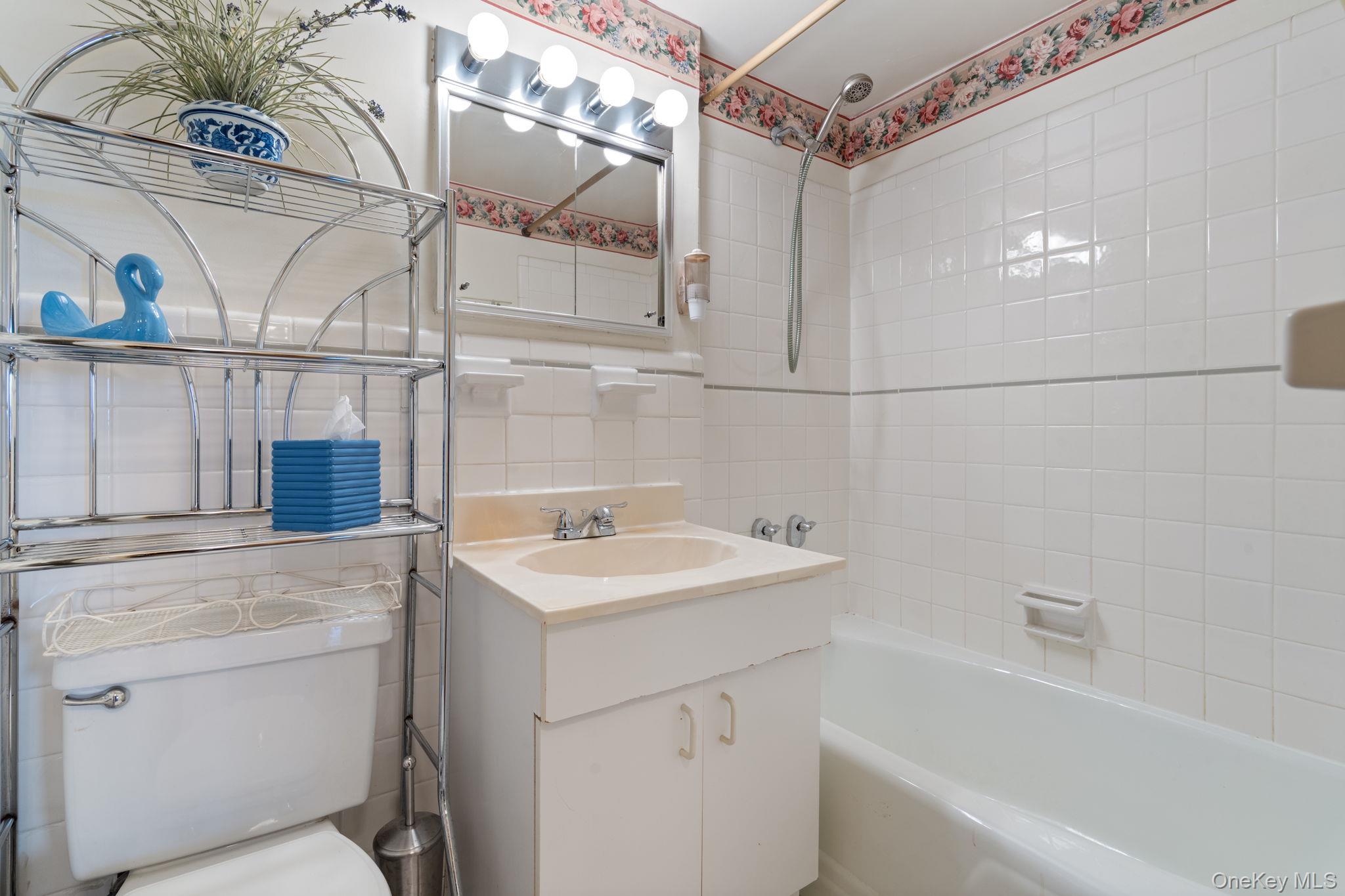 61-15 97th Street, Unit 12H Queens, NY 11374 - Photo 14 of 23 Full bath with vanity, shower / bathtub combination, tile walls, and tasteful backsplash