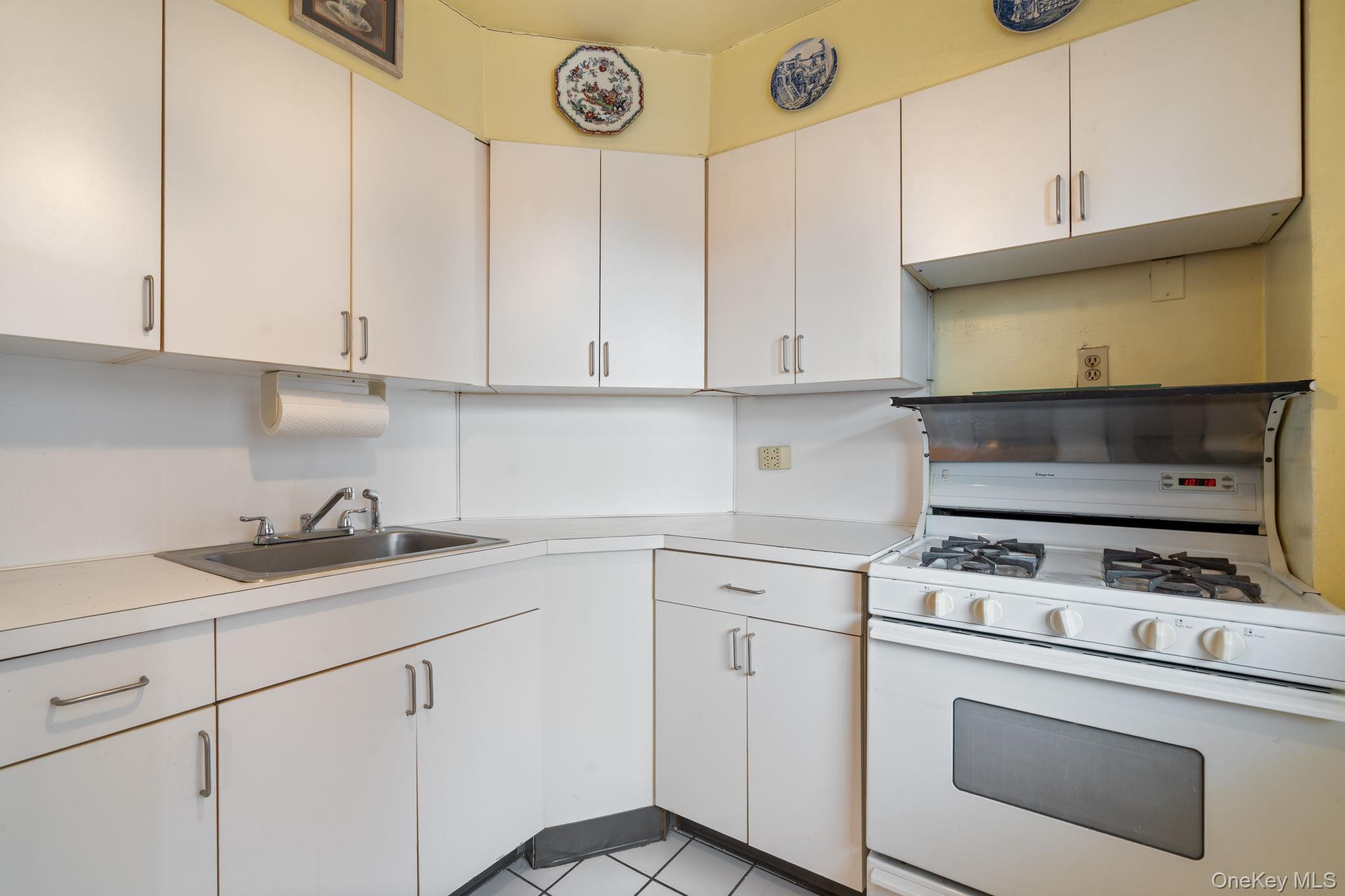 61-15 97th Street, Unit 12H Queens, NY 11374 - Photo 10 of 23 Kitchen featuring gas range gas stove, white cabinets, and light countertops