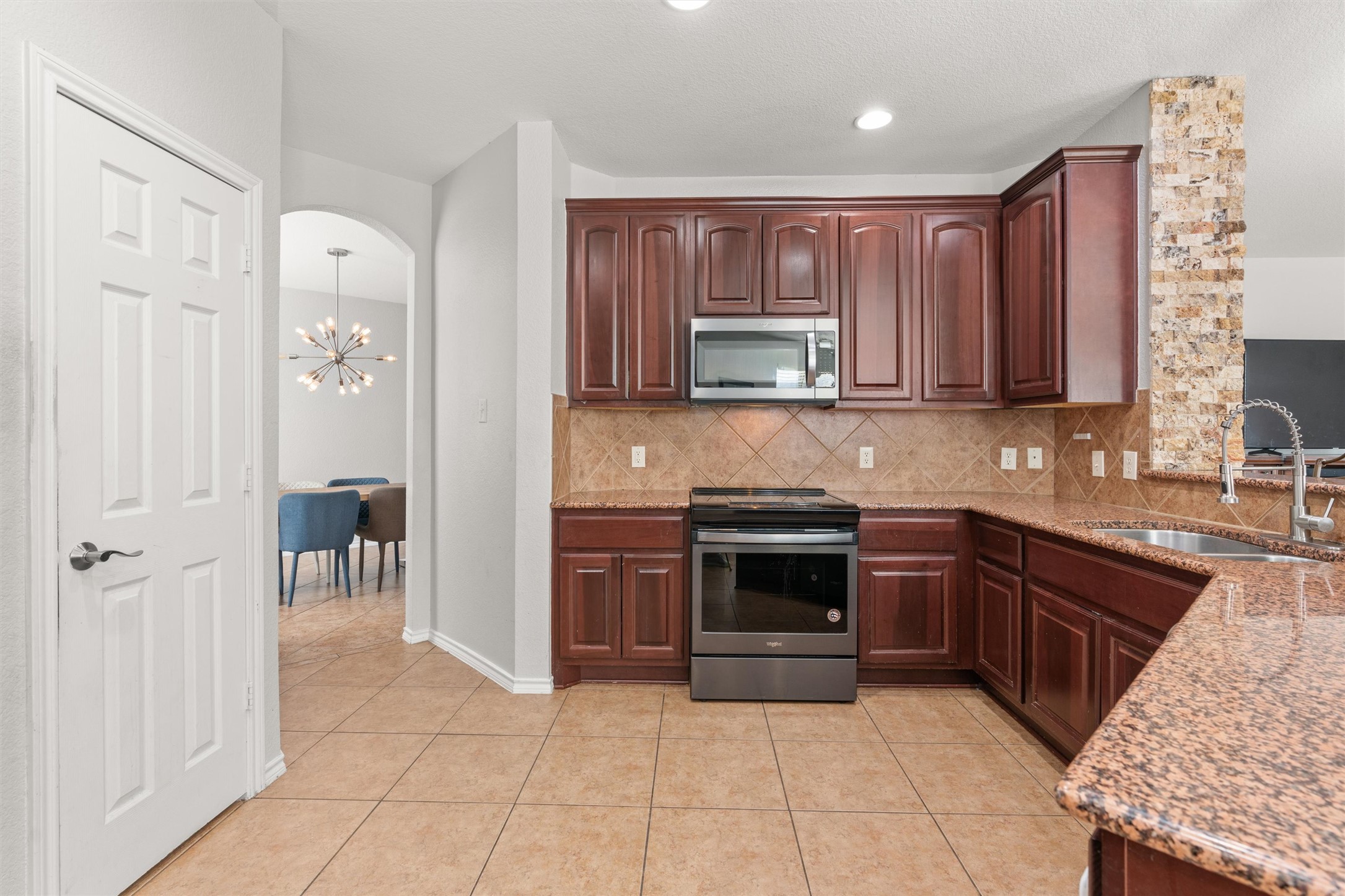 400 Red Hawk Drive Leander, TX 78641 - Photo 11 of 36 Kitchen featuring stainless steel appliances, light stone counters, light tile patterned floors, arched walkways, and hanging lights