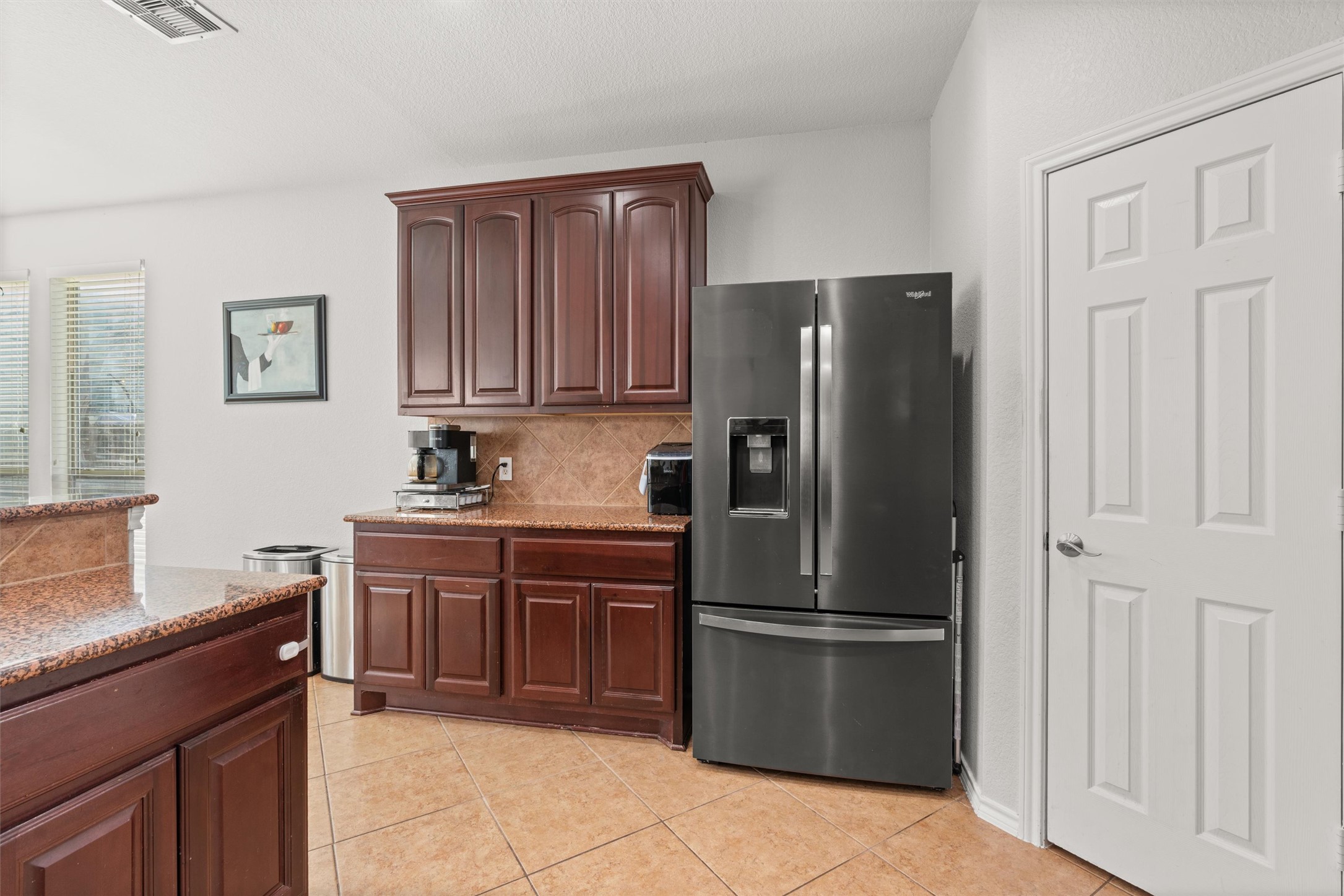 400 Red Hawk Drive Leander, TX 78641 - Photo 13 of 36 Kitchen with stainless steel fridge, light stone countertops, light tile patterned floors, backsplash, and dark wood finish cabinets