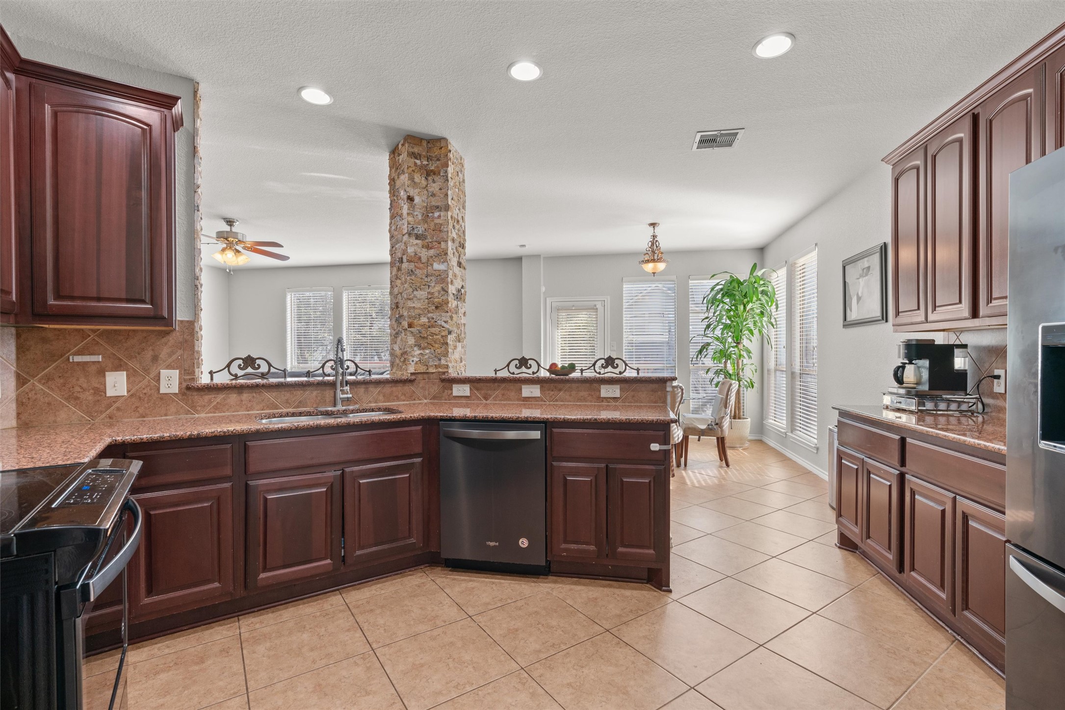 400 Red Hawk Drive Leander, TX 78641 - Photo 14 of 36 Kitchen featuring tasteful backsplash, dark wood finish cabinetry, stainless steel appliances, dark stone counters, and light tile patterned floors