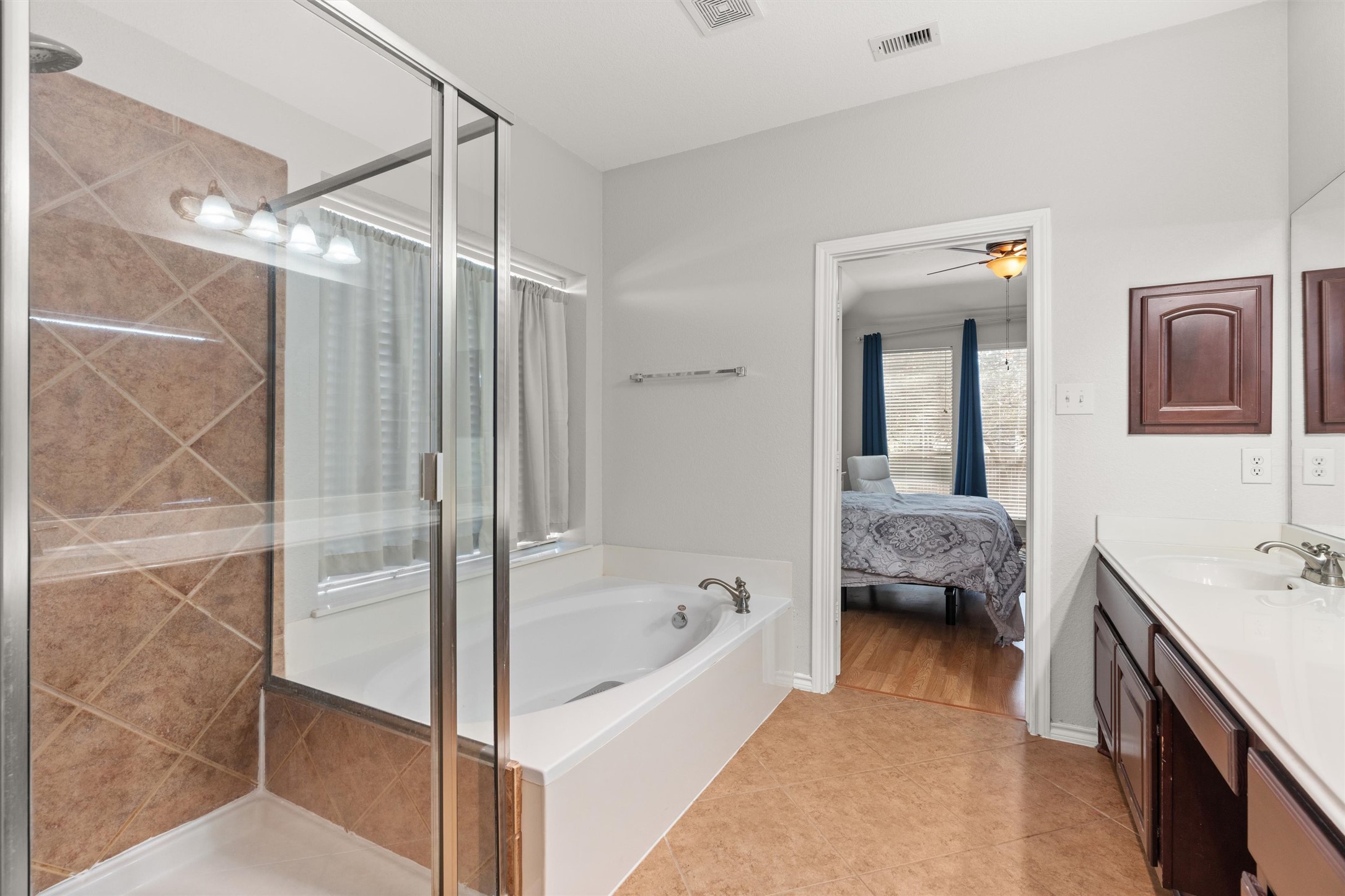 400 Red Hawk Drive Leander, TX 78641 - Photo 18 of 36 Ensuite bathroom featuring vanity, light tile patterned floors, a shower stall, and a garden tub