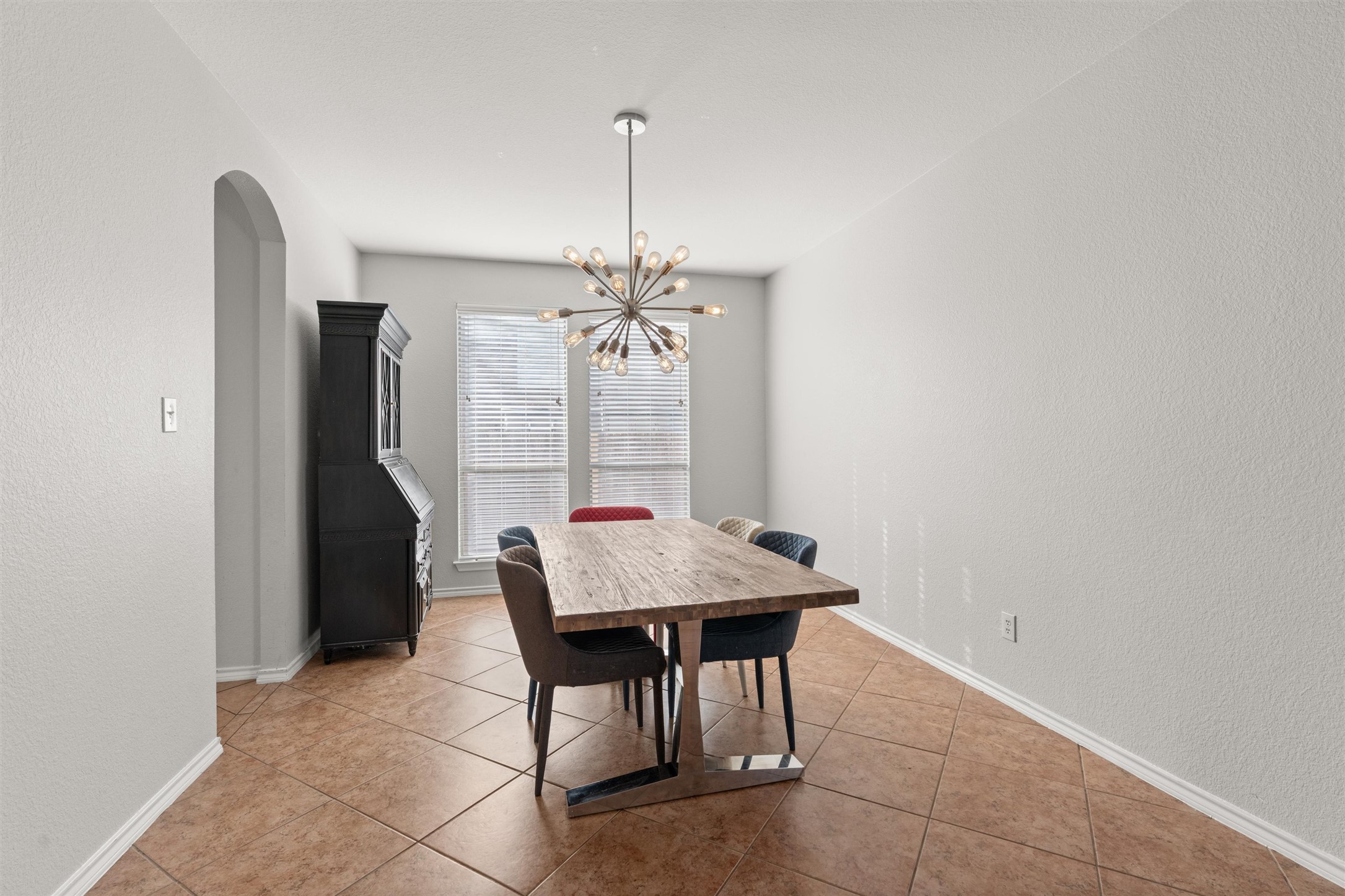 400 Red Hawk Drive Leander, TX 78641 - Photo 5 of 36 Dining area with a textured wall, a chandelier, arched walkways, and light tile patterned floors