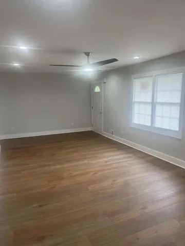 an empty room with wooden floor and windows with curtains