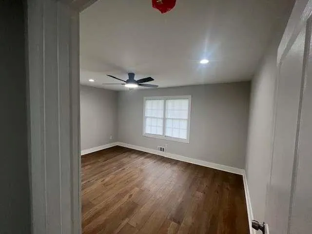 an empty room with wooden floor and windows