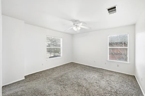 an empty room with windows and fan
