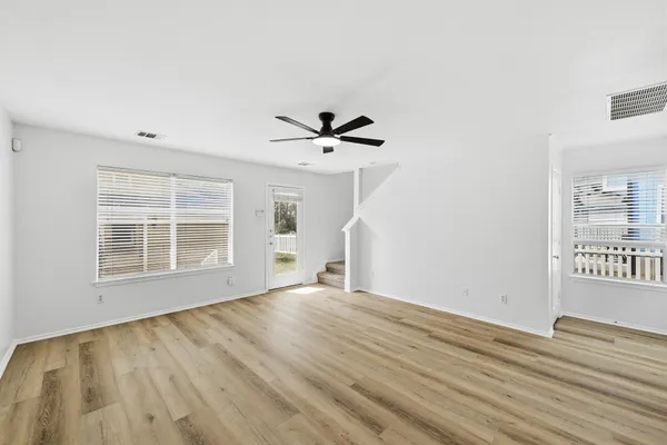 a view of empty room with wooden floor and fan