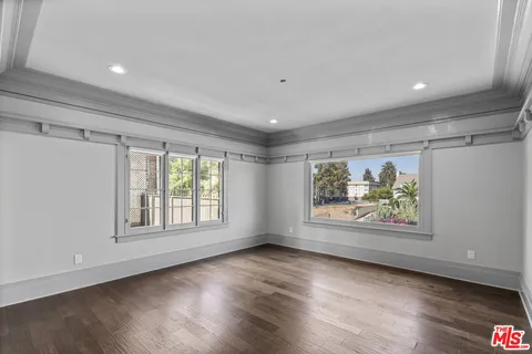 a view of an empty room with a window and wooden floor