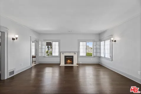an empty room with windows a fireplace and wooden floor