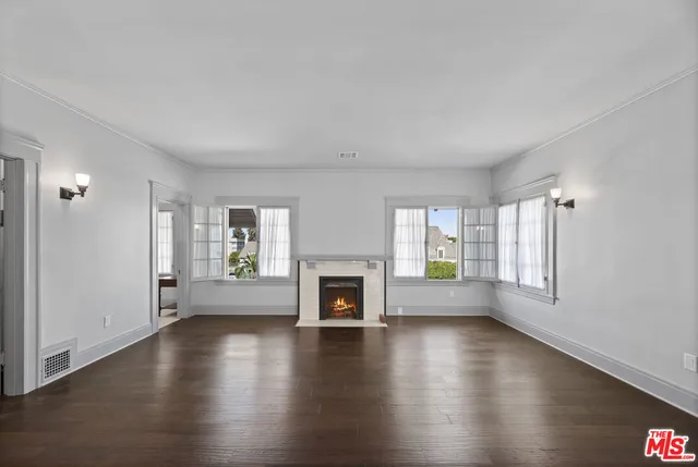 an empty room with windows a fireplace and wooden floor