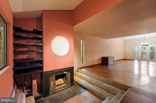 a view of an empty room with a fireplace and wooden floor