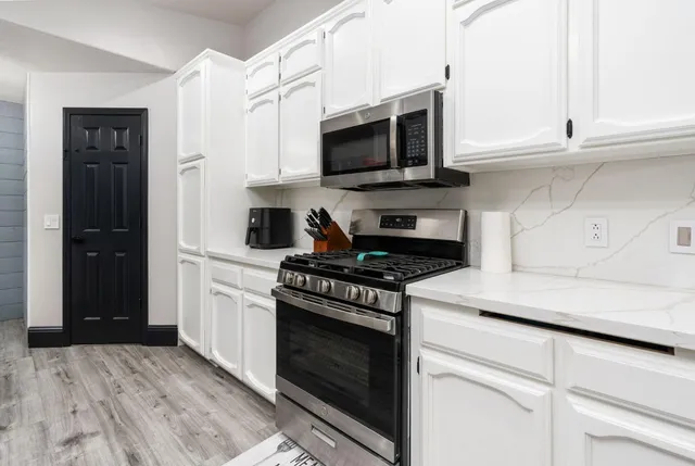 a kitchen with stainless steel appliances granite countertop white cabinets and black stove top oven with granite countertops