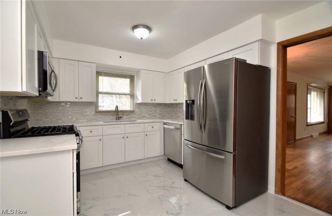 3681 Brinkmore Road Cleveland Heights, OH 44121 - Photo 10 of 27 Kitchen featuring light tile floors, sink, stainless steel appliances, white cabinets, and backsplash