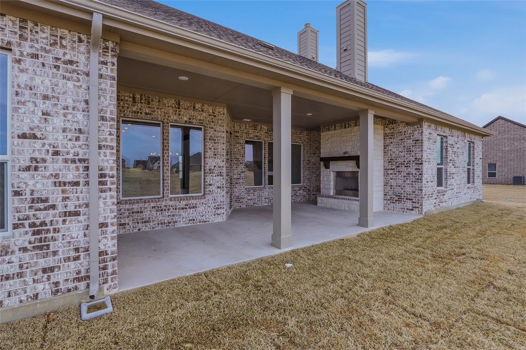 810 Vly Rdg Road Van Alstyne, TX 75495 - Photo 34 of 39 Back of property featuring a fireplace, a patio area, brick siding, and a lawn