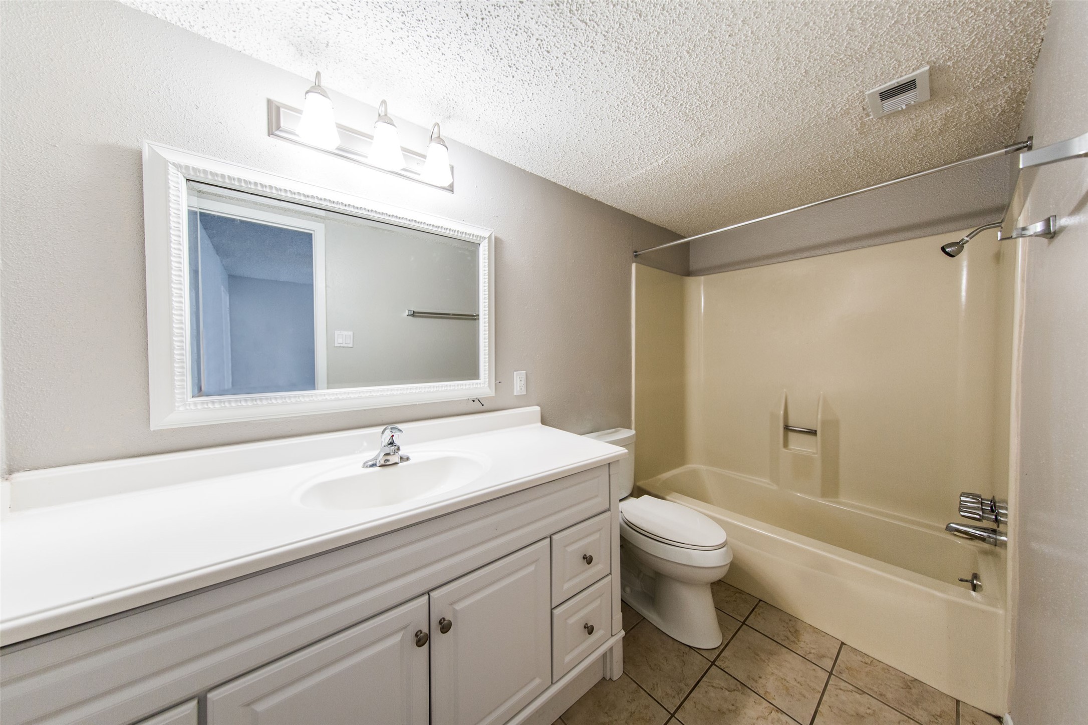 108 West 45th Street, Unit 110 Austin, TX 78751 - Photo 6 of 7 Bathroom featuring shower / tub combination, vanity, a textured ceiling, and light tile patterned flooring