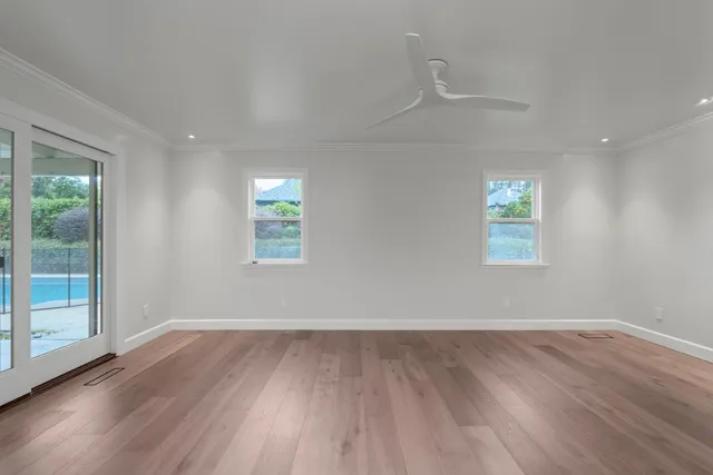 an empty room with wooden floor and windows