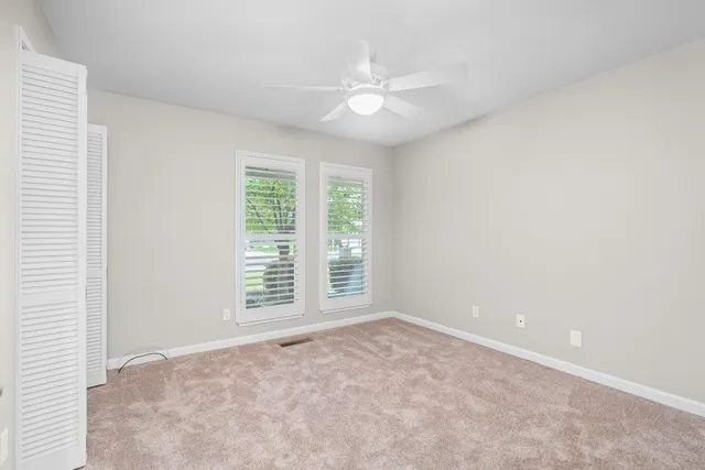an empty room with windows and fan