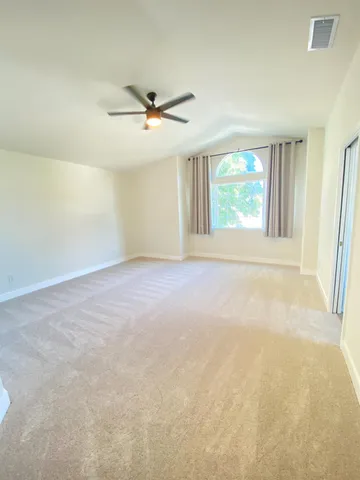 an empty room with windows and fan