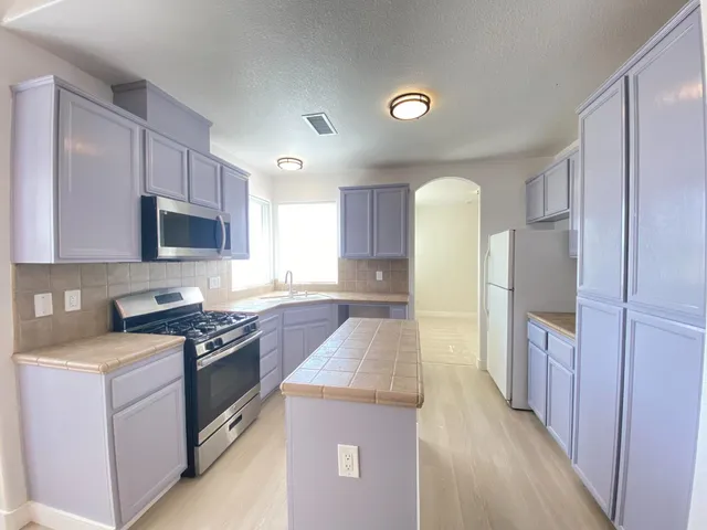 a kitchen with stainless steel appliances granite countertop a stove a sink and a refrigerator