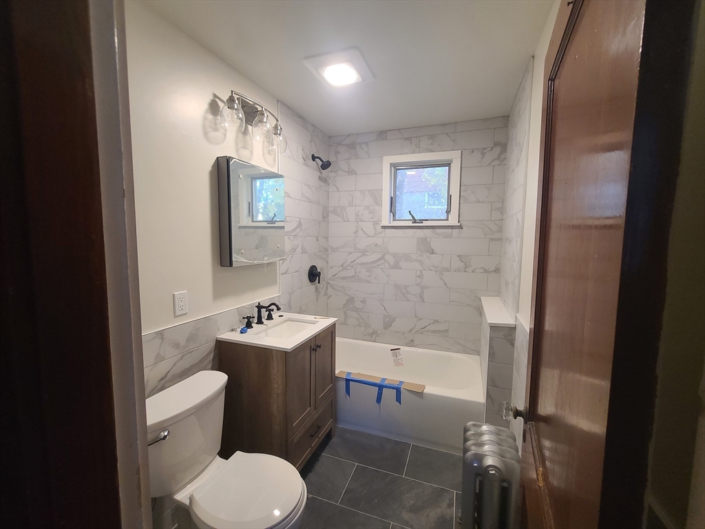 28 Tip Top Street, Unit 1 Boston, MA 02135 - Photo 3 of 13 a bathroom with a sink toilet and tub
