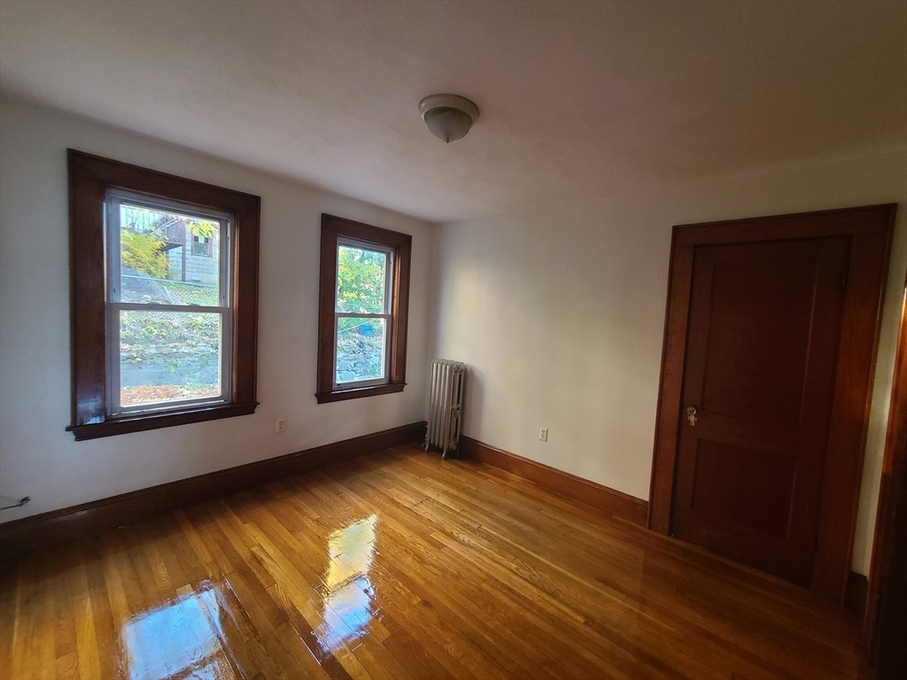 28 Tip Top Street, Unit 1 Boston, MA 02135 - Photo 7 of 13 an empty room with wooden floor and windows