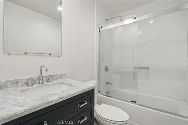 a bathroom with a granite countertop sink a toilet and shower