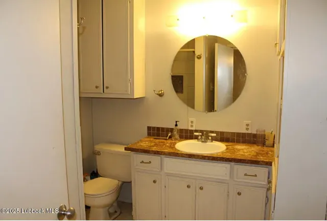 a bathroom with a granite countertop toilet sink and mirror