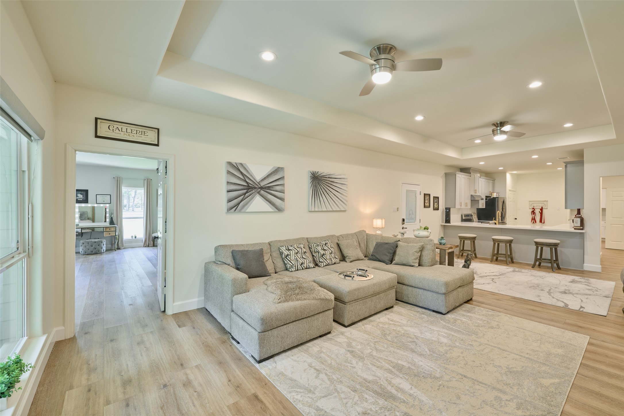 2218 Honea Egypt Road Magnolia, TX 77354 - Photo 45 of 50 This is a modern, open-concept living space with a combined living room and kitchen area, featuring hardwood floors, neutral tones, and recessed lighting. The room is well-lit and includes contemporary furnishings and decor.