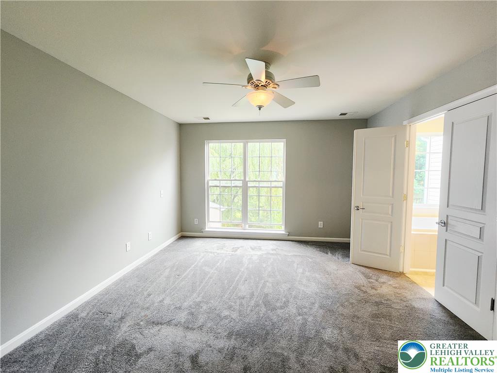 8513 Gateway Road Breinigsville, PA 18031 - Photo 26 of 45 A generously sized bedroom with ample natural light, featuring plush carpeting and a versatile ceiling fan.