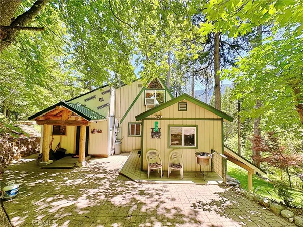 a backyard of a house with table and chairs under an umbrella
